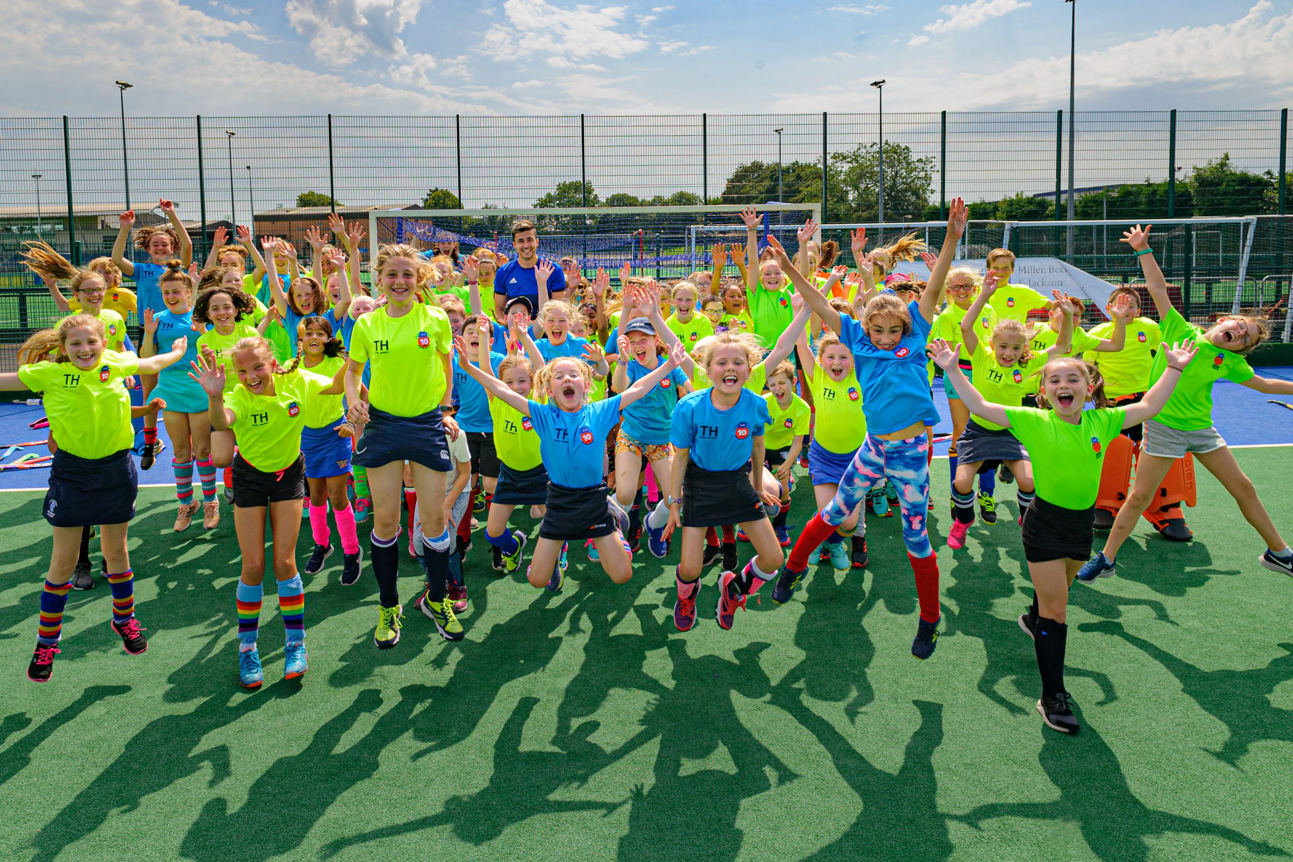 Children celebrating together on the pitch at a Spider Hockey camp