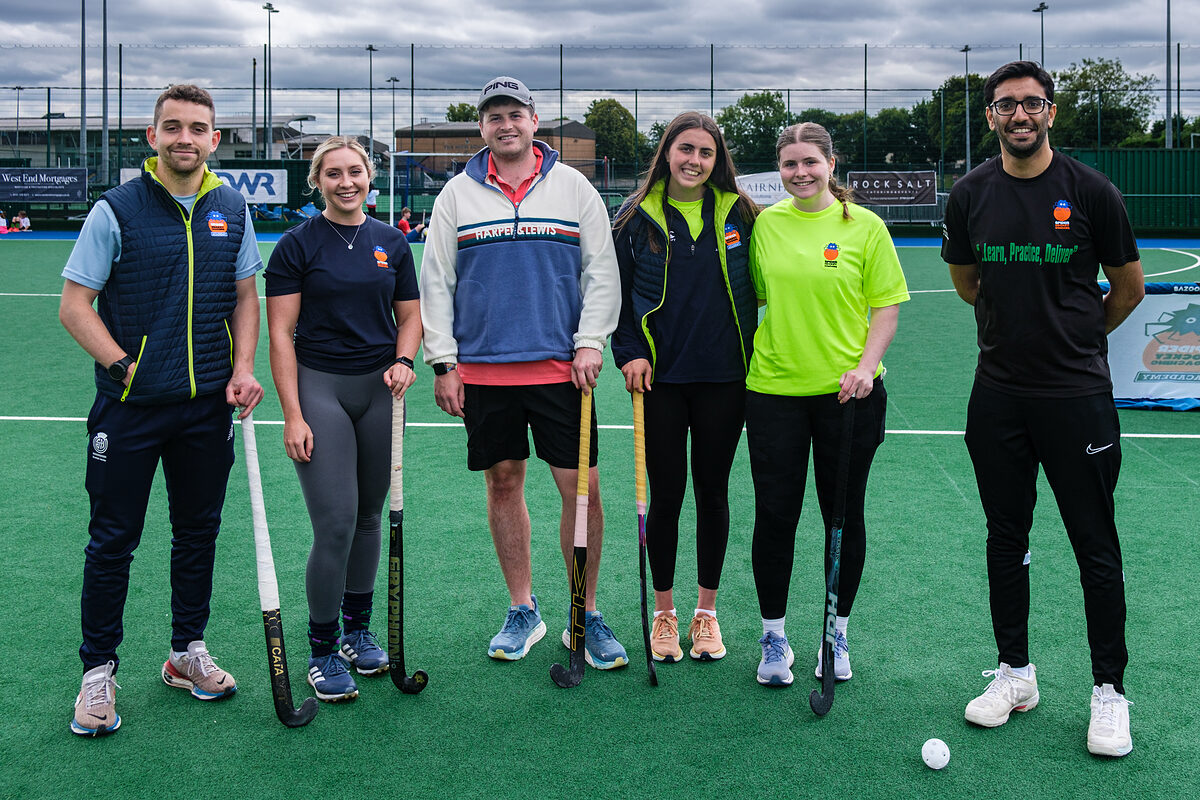 The Spider Hockey coaching team on the pitch with their sticks