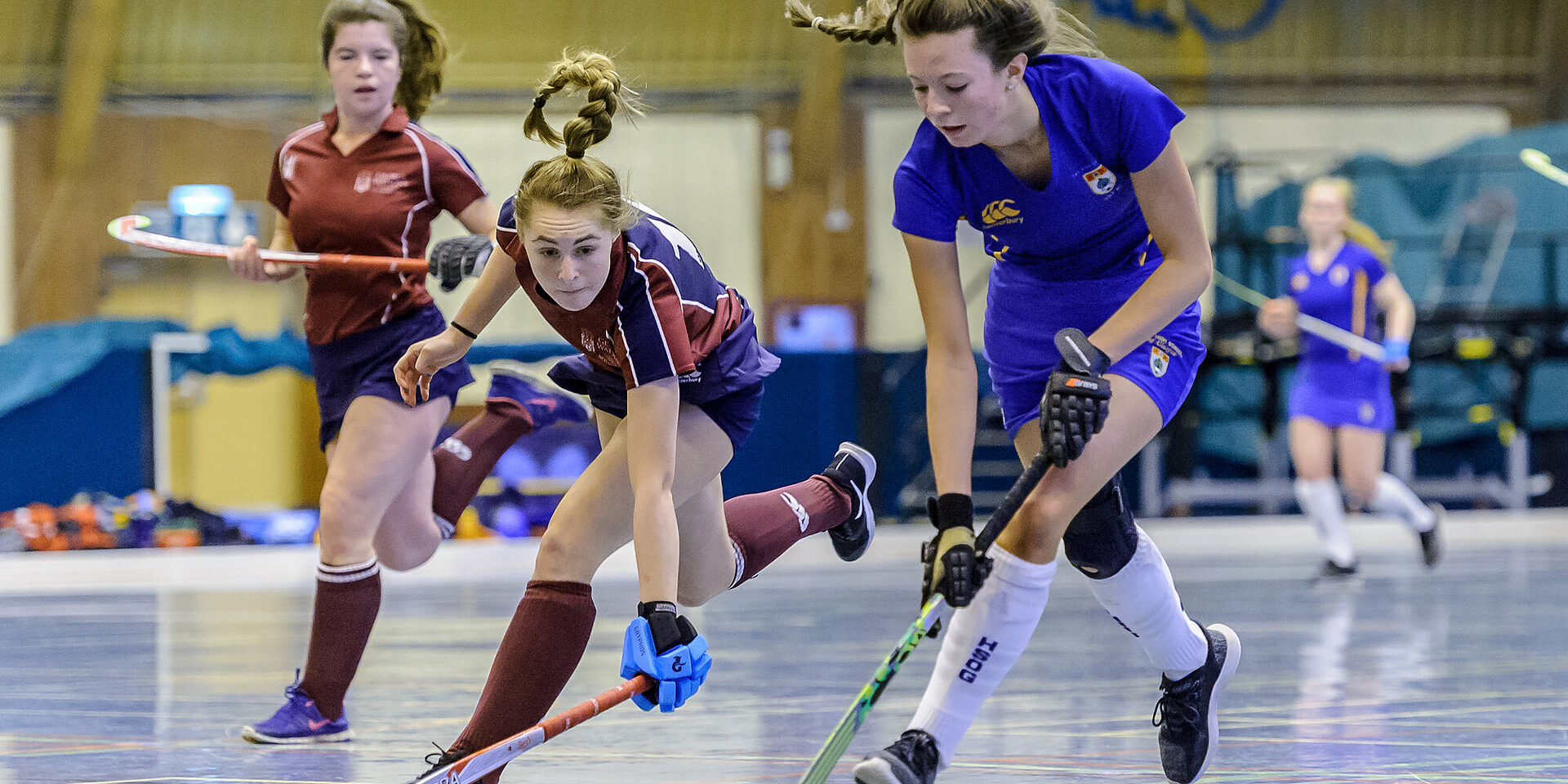 Players competing for the ball during an indoor hockey match